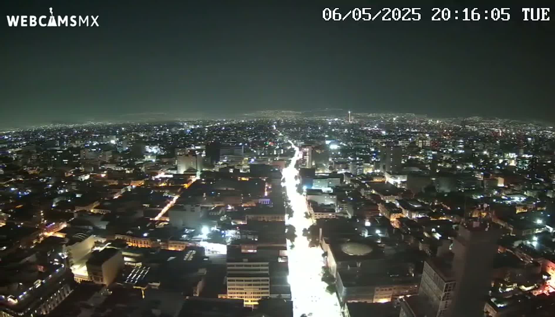 A brightly lit city at night stretches out under a clear, dark sky.