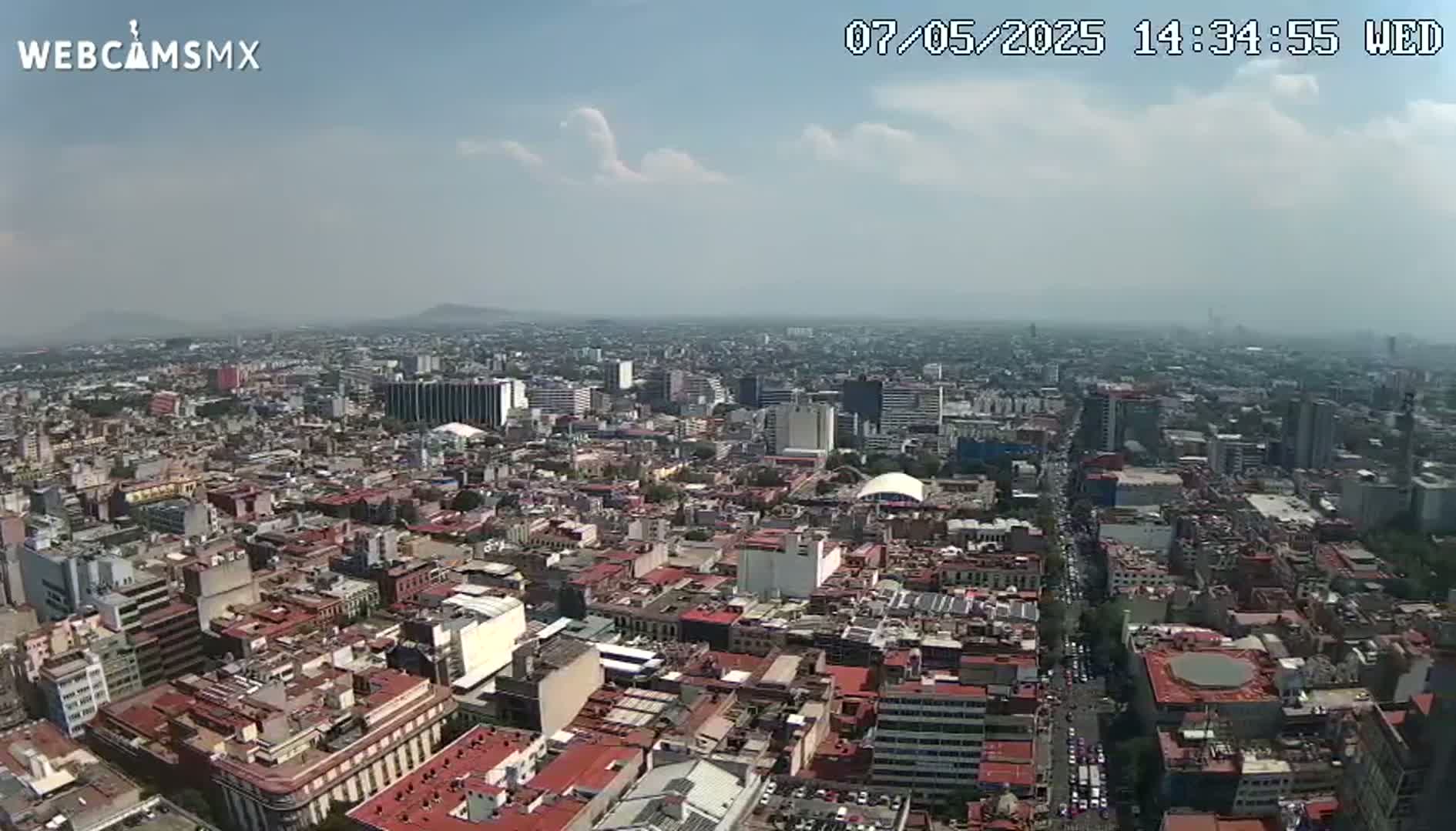 An aerial view shows a sprawling city under a partly cloudy sky.