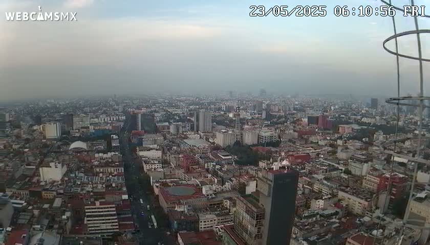A hazy, overcast view of a sprawling city from a high vantage point, showing numerous buildings and streets.