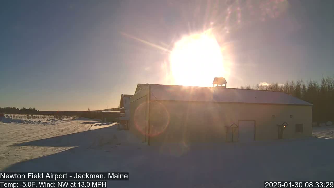 A snow-covered building is brightly lit by the low winter sun, with a NW wind at 13.0 mph.