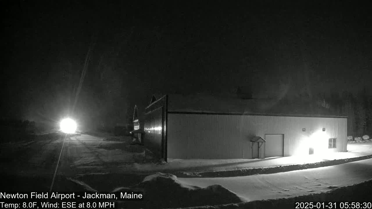 A long, low building is illuminated at night in a snowy landscape under a dark sky.