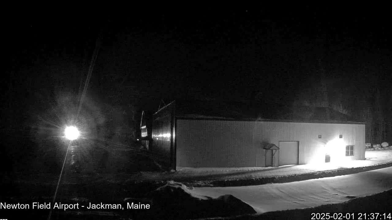 A long, light-colored building is illuminated at night in snowy conditions.