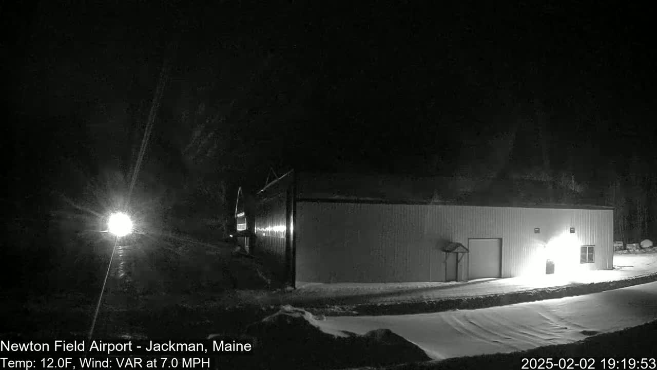 A long, low building is illuminated at night in a snowy landscape under a dark sky.