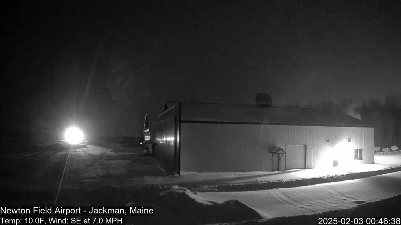 A long, low building is illuminated at night in a snowy landscape under a dark sky.