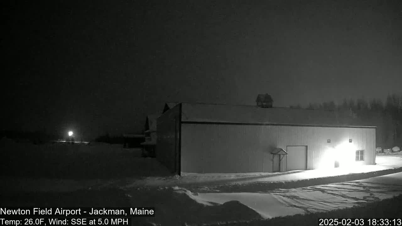 A large, single-story building is illuminated at night in a snowy landscape under a dark sky.