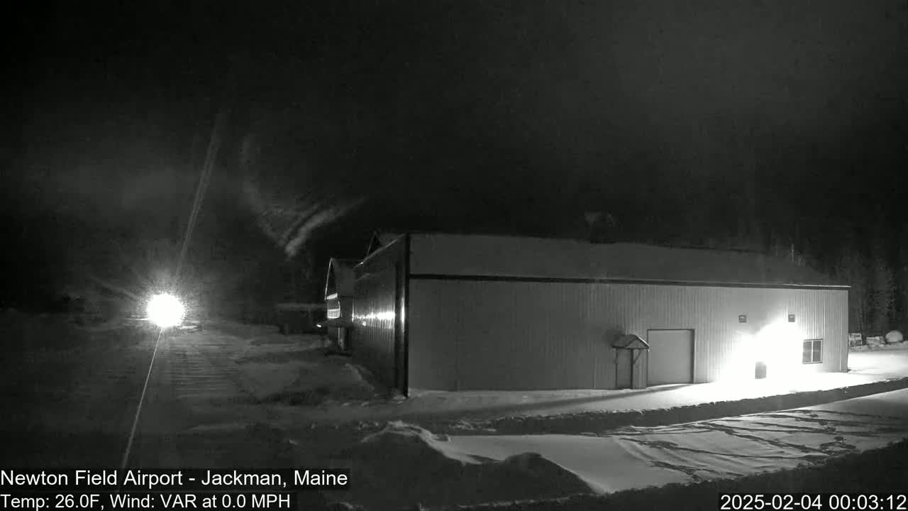 A long, low building is illuminated at night in a snowy landscape under a dark sky.