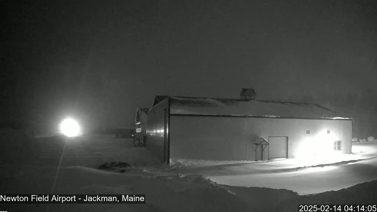 A large, snow-covered building is illuminated at night in snowy conditions.