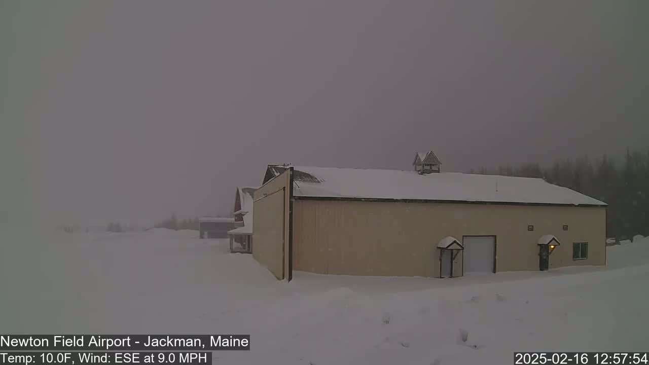 A tan hangar sits in a snow-covered landscape under an overcast sky with a 9 mph ESE wind and 10°F temperature.