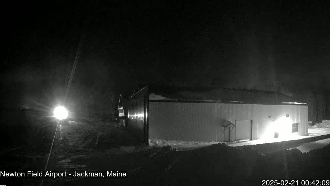 A large, light-colored building is illuminated at night in snowy conditions.