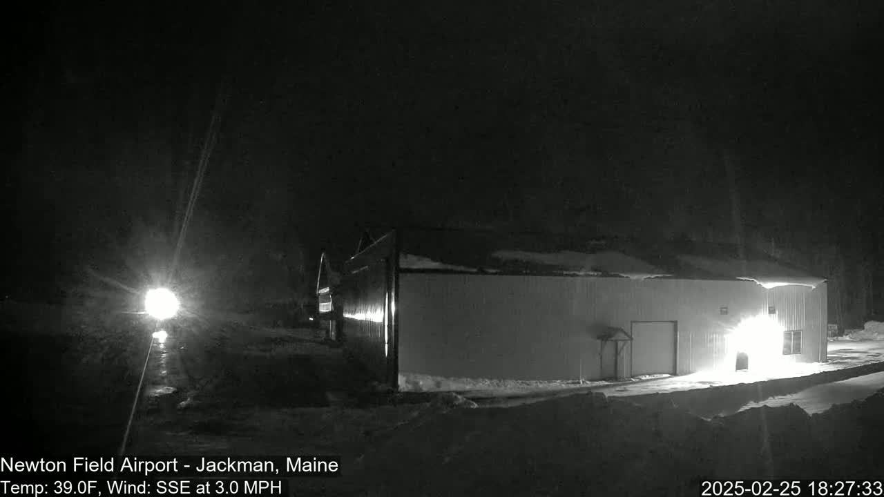 A large, light-colored building is illuminated at night in snowy conditions.