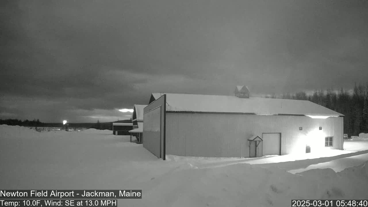 A large, snow-covered building stands in a snowy landscape under a dark, overcast sky, with a slight southeast wind.