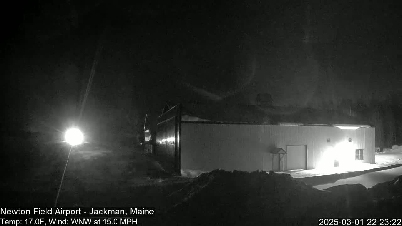 A snow-covered building is illuminated at night under a dark, possibly snowy sky.