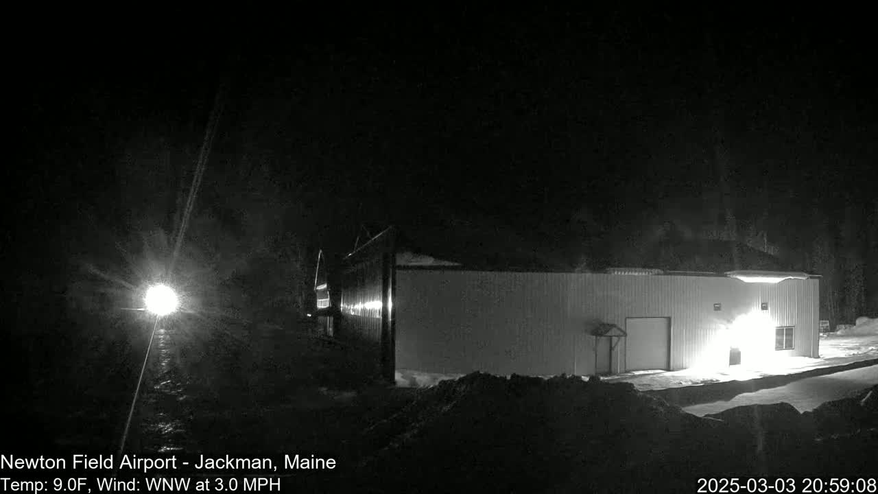 A brightly lit building stands in a snowy, nighttime landscape under a dark sky.