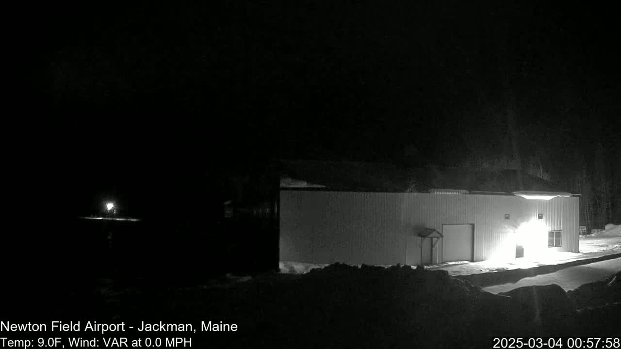 A brightly lit building stands in a snowy, dark nighttime scene.
