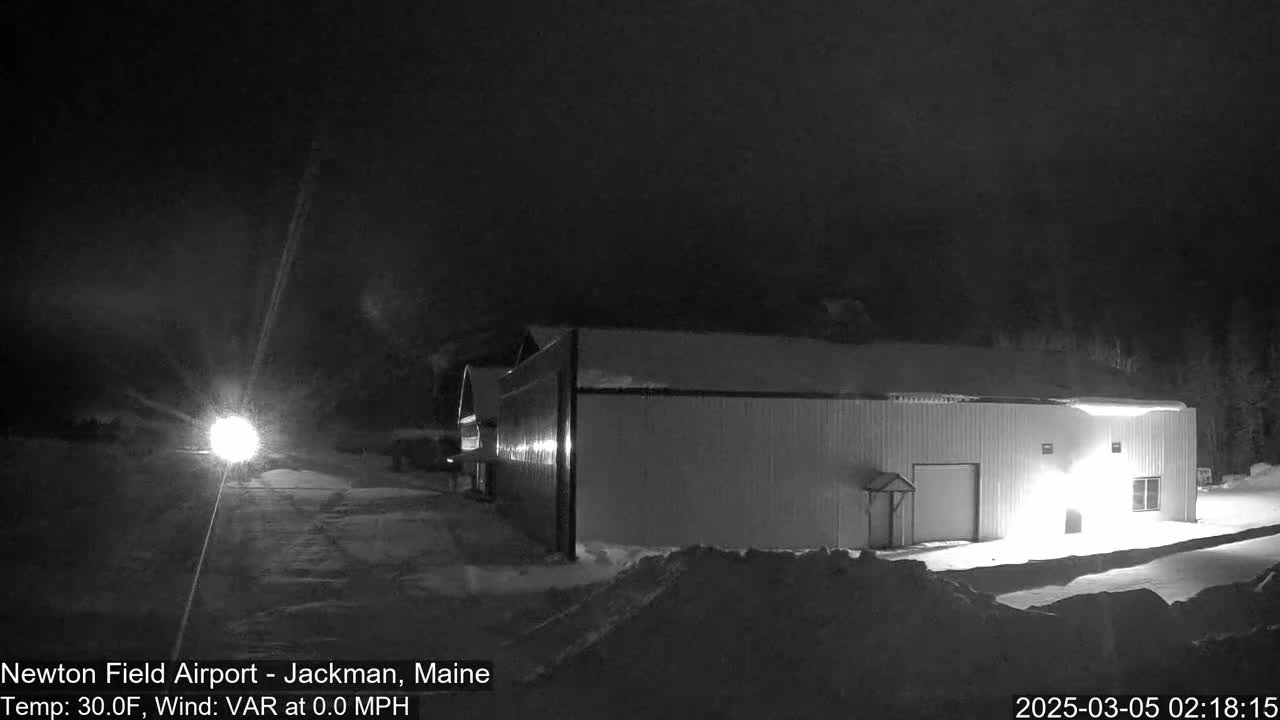 A long, light-colored building is illuminated at night in snowy conditions.