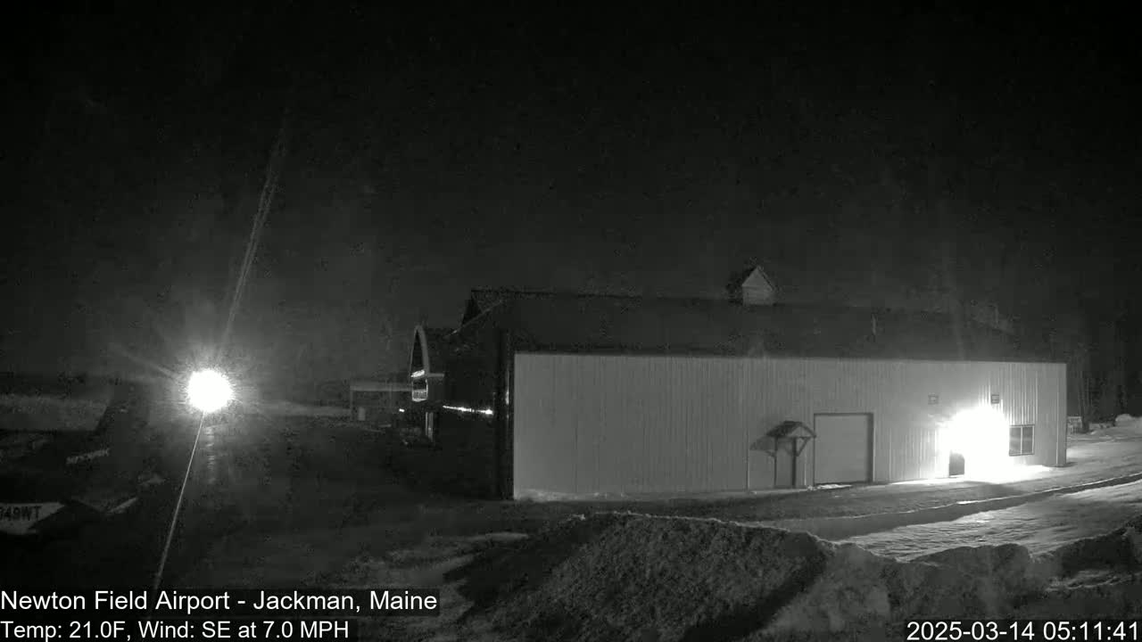 A large, light-colored building is illuminated at night under a dark sky with a southeast wind of 7.0 mph and a temperature of 21 degrees Fahrenheit.