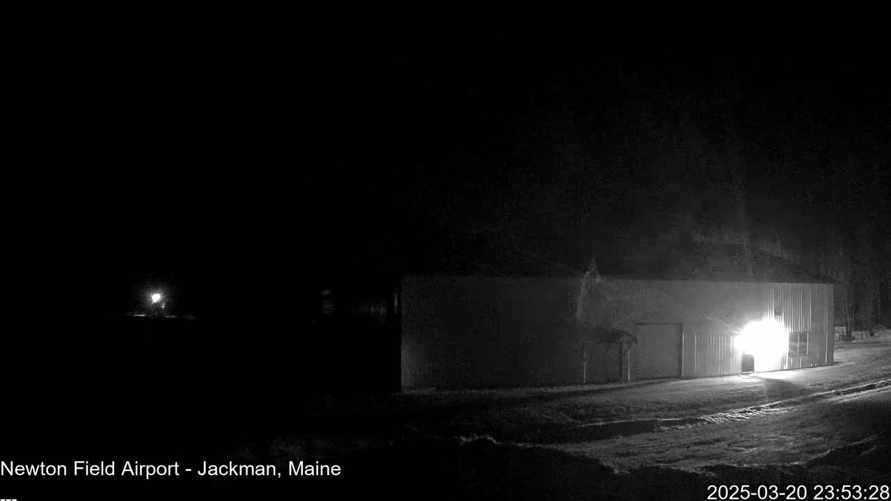 A brightly lit building is visible in the foreground of a dark, snowy nighttime scene.