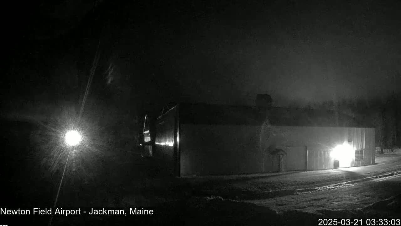 A long, low building is illuminated at night under a dark, possibly snowy or hazy sky.