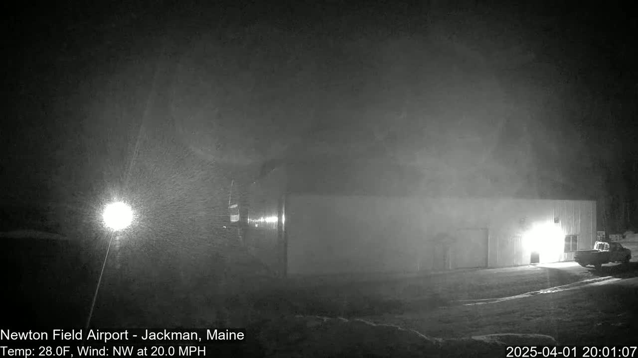 A large, light-colored building is visible in the snow at night, under a NW wind of 20 mph.