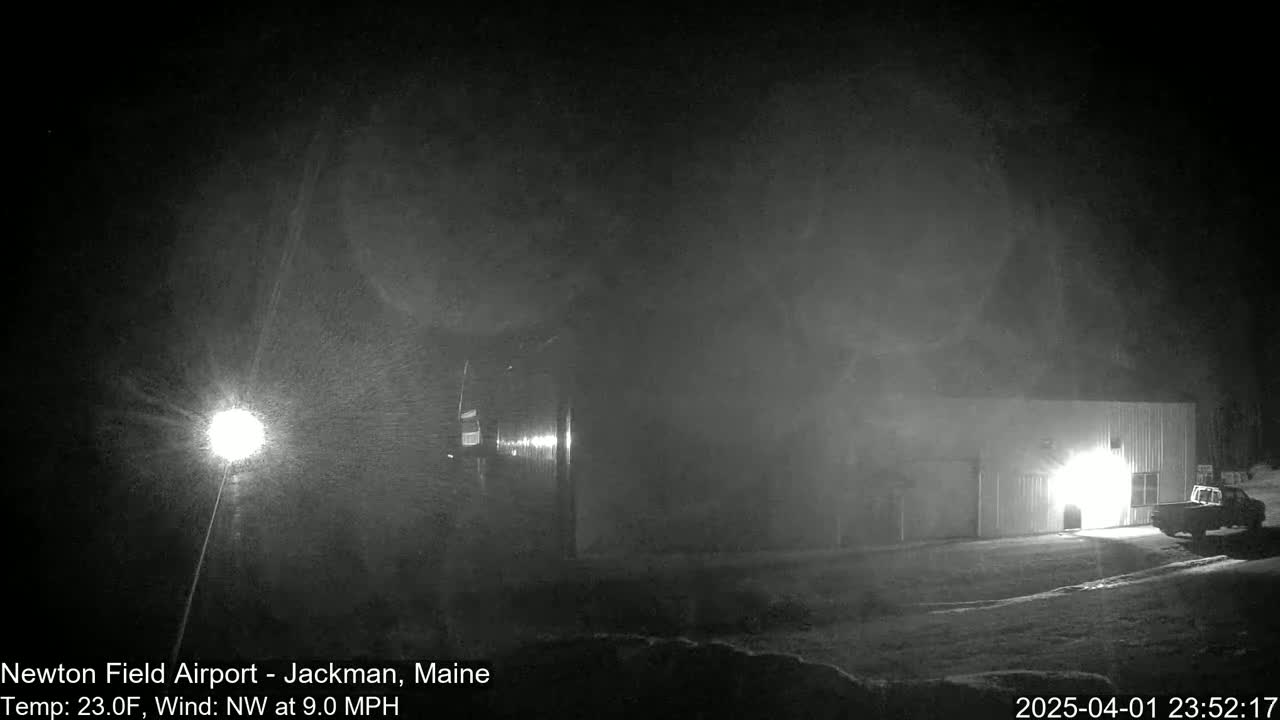 A nighttime scene shows a building with a vehicle parked nearby in snowy conditions with a northwest wind.