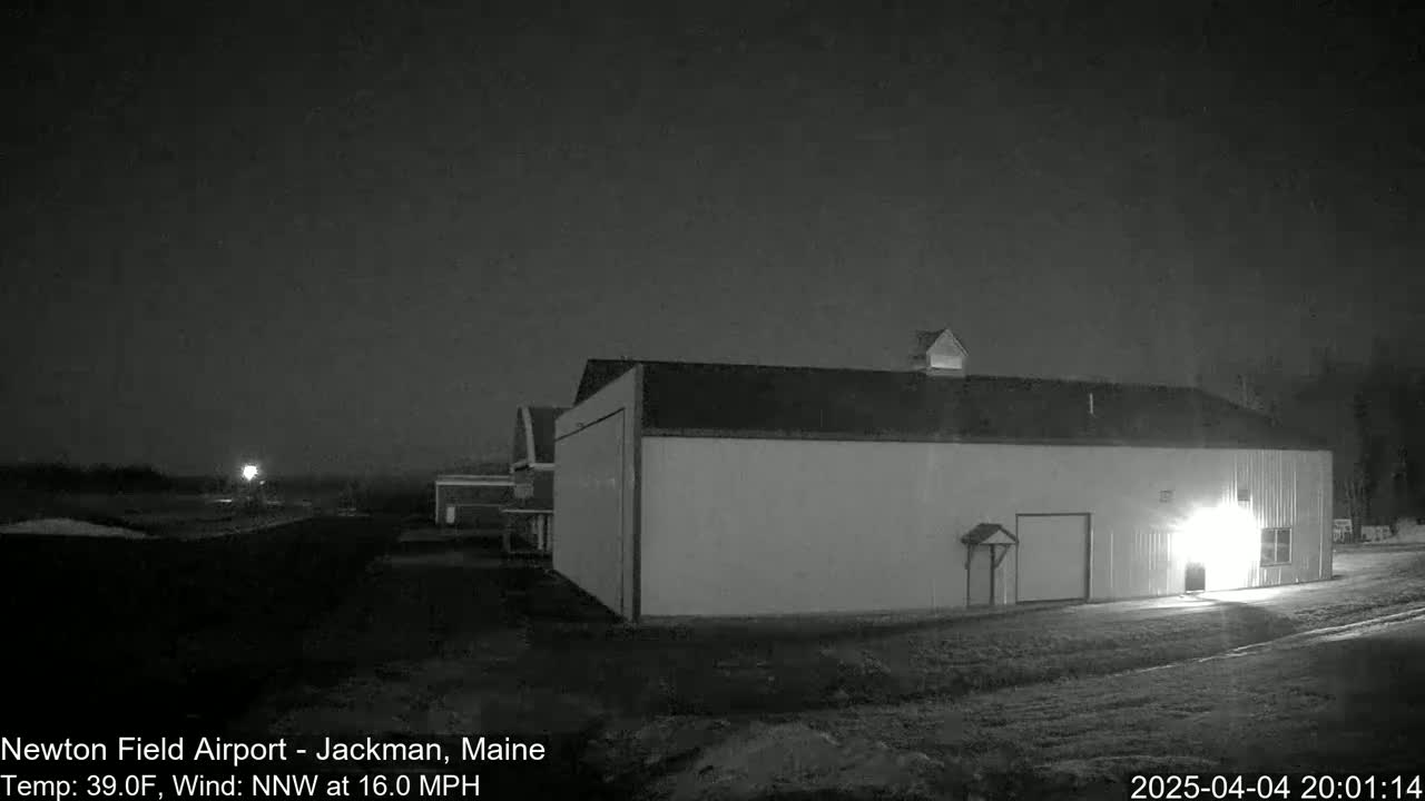 A large, light-colored building is illuminated at night under a dark, clear sky with a northwest wind blowing at sixteen miles per hour and a temperature of thirty-nine degrees Fahrenheit.