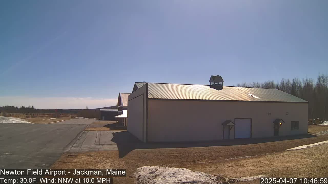 A large tan building with a green metal roof sits on a mostly clear day with a light wind.
