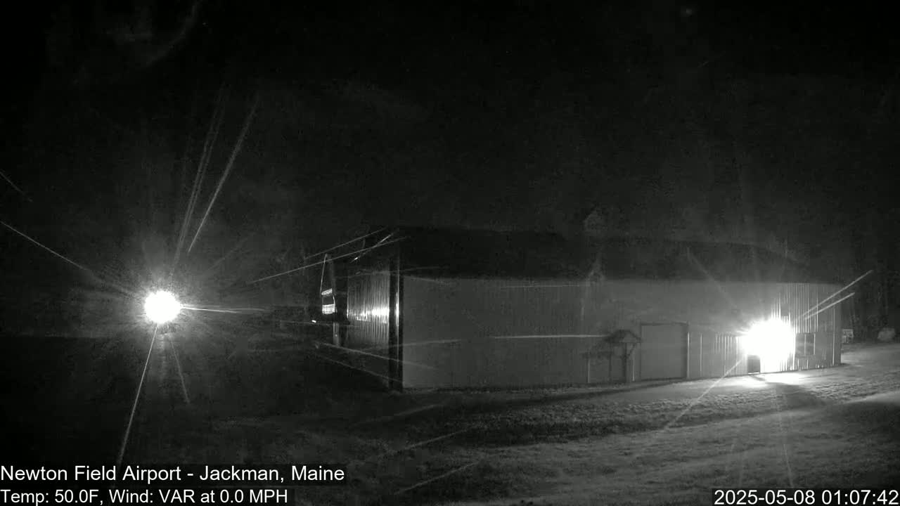 A large, light-colored building is illuminated at night under a dark, possibly snowy sky.
