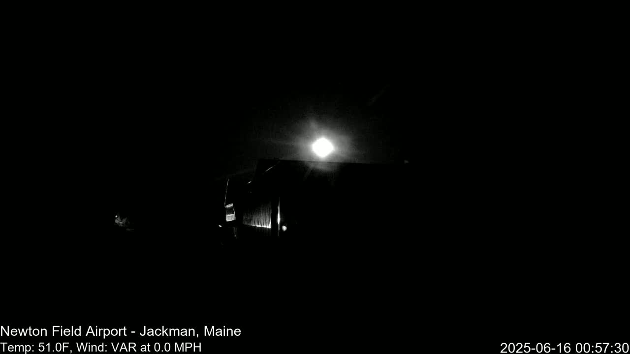 A bright moon shines in a dark, nighttime sky above a silhouetted structure.
