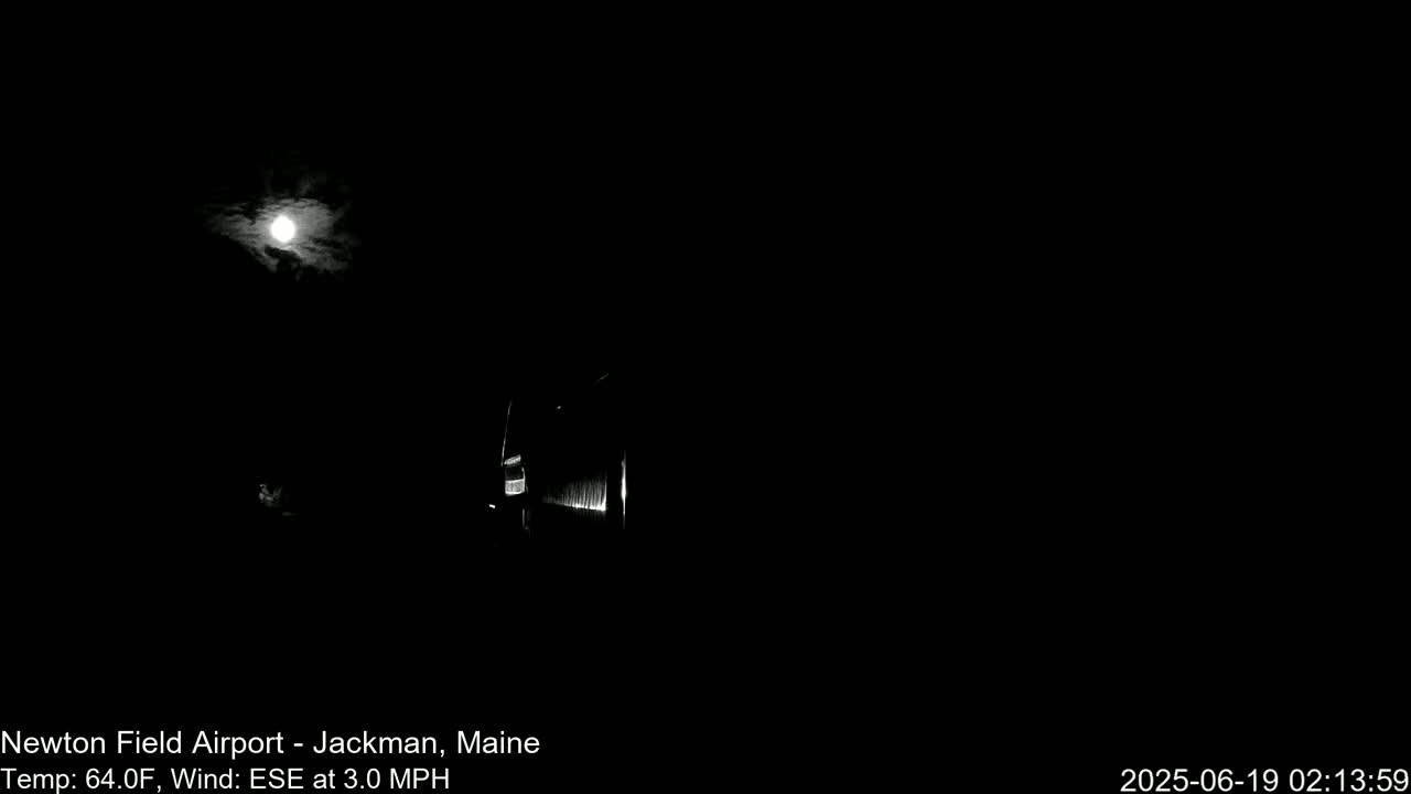 A nighttime image shows a bright moon partially obscured by clouds and a dimly lit structure in the foreground under a 64°F sky with a 3.0 mph ESE wind.