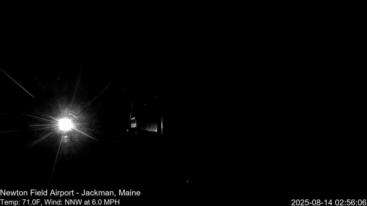 A bright light flares in the center of a dark, nighttime scene with a hint of structure to the right, under a calm, 71°F night with a 6 mph north-northwest wind.