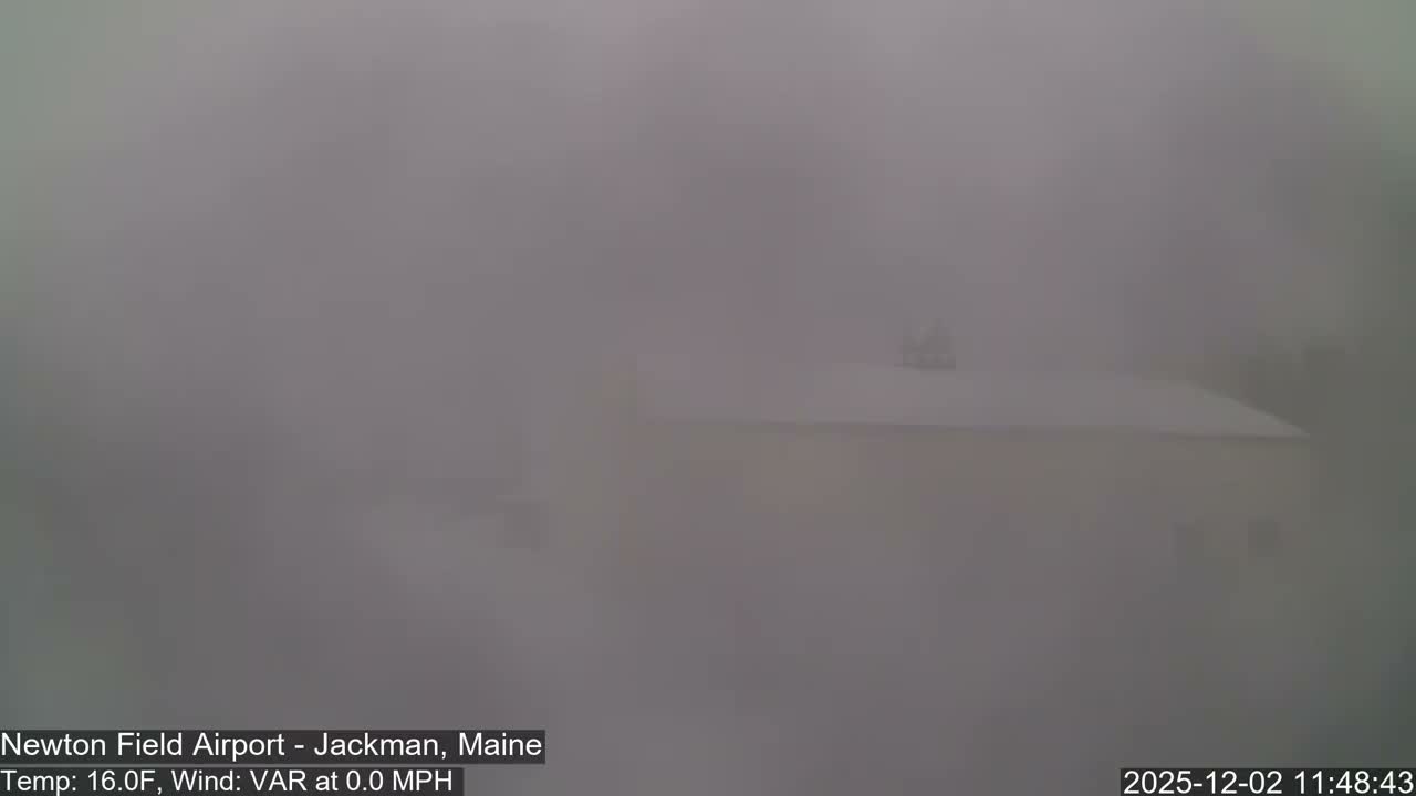 The image shows an extremely foggy or misty outdoor scene with very low visibility, where the faint outline of a building with a sloped roof can barely be distinguished through the thick atmospheric conditions.