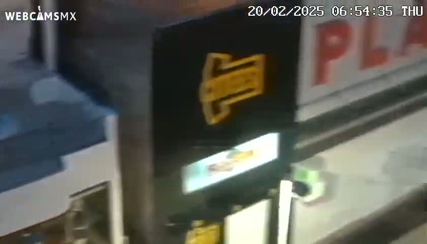 A blurry image shows a dark-colored machine with a yellow logo, partially visible against a wall with a red sign.