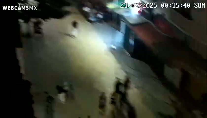 A nighttime, high-angle view shows a street with several people walking around.