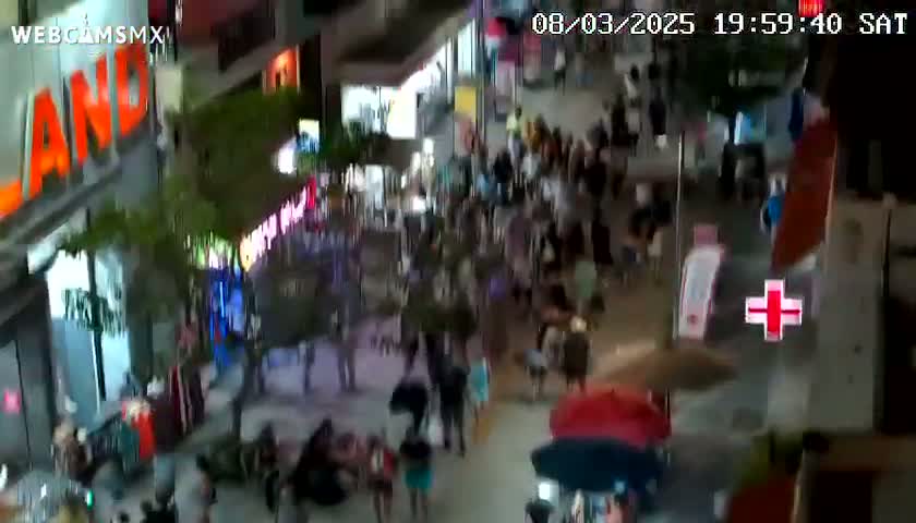 A nighttime overhead view of a crowded outdoor pedestrian area with many people walking around and shops on either side.