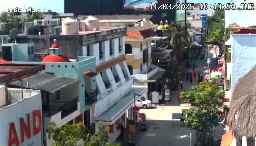 A sunny day reveals a bustling pedestrian street lined with colorful buildings, showcasing a mix of architectural styles and businesses.