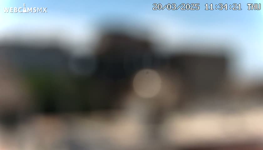 A blurry outdoor image shows a dark building under a mostly clear, bright sky.