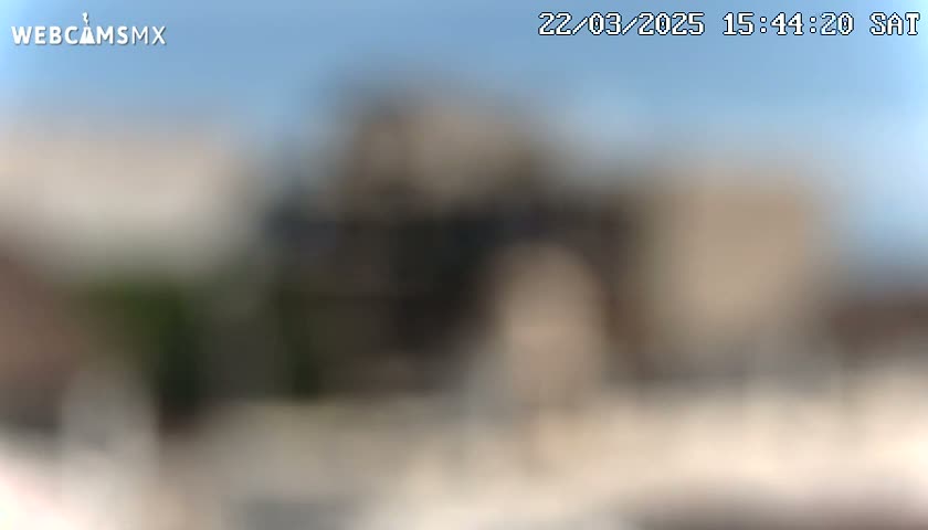 A blurry outdoor image shows a building under a clear blue sky.