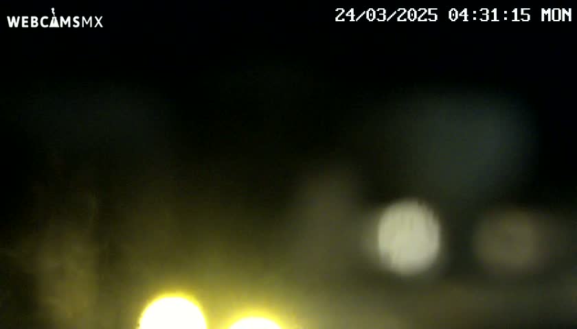 At night, blurry yellow headlights are visible through a hazy, dark atmosphere.