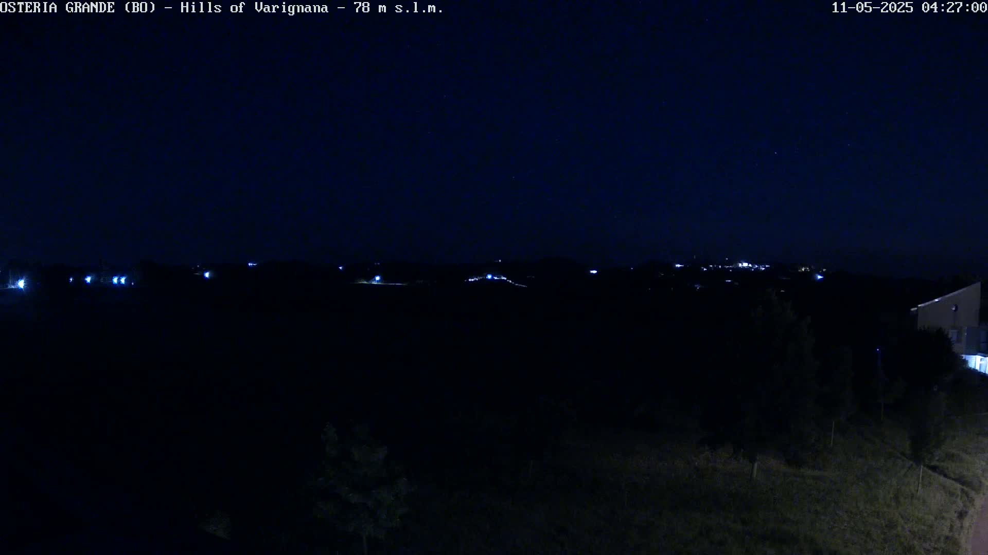 A nighttime view of distant lights on a hill under a clear, dark sky.
