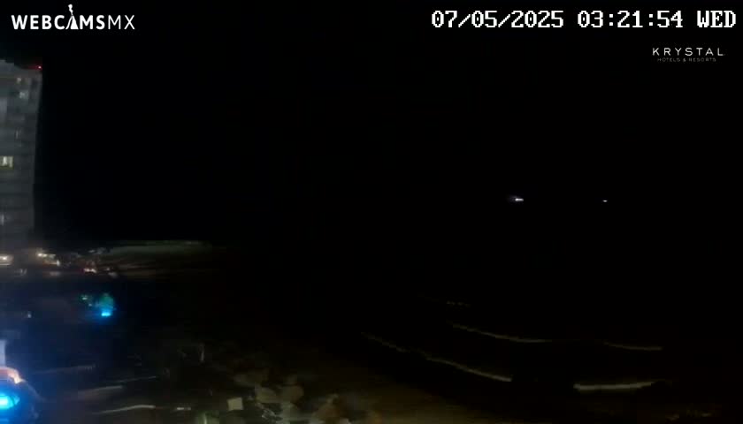 A dark nighttime scene shows a tall building to the left and a dimly lit, possibly beach-like area to the right.