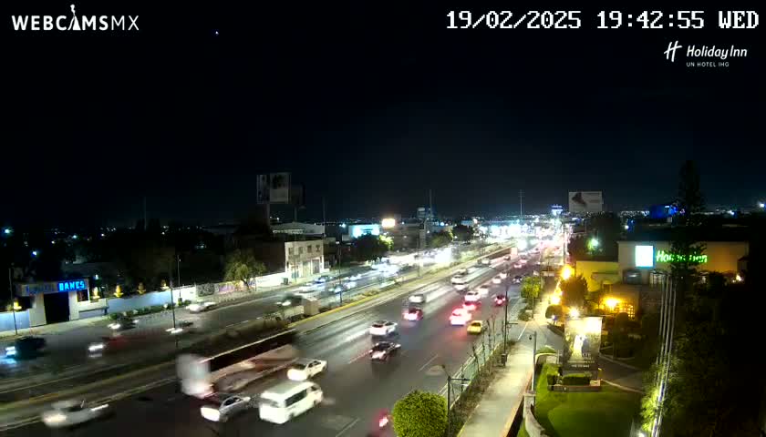 A nighttime view of a multi-lane highway with moderate traffic under a clear sky.