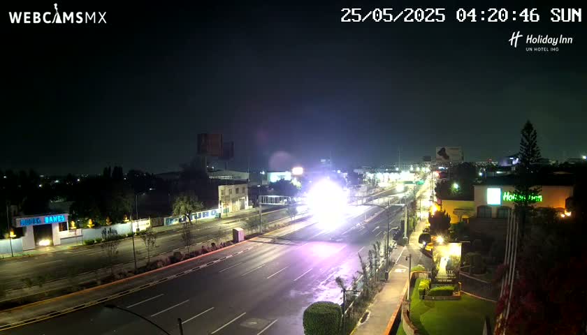 A nighttime, high-angle view of a brightly lit city street at night, with a large, bright light source in the middle of the road.