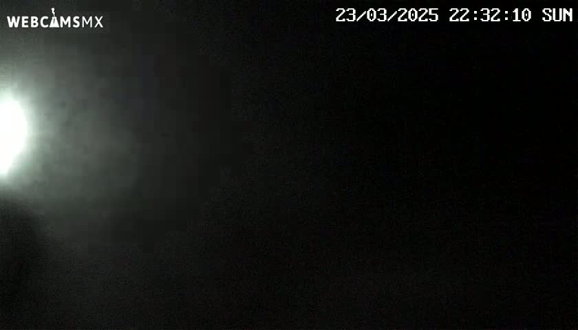 A bright light shines through a hazy, dark night sky.