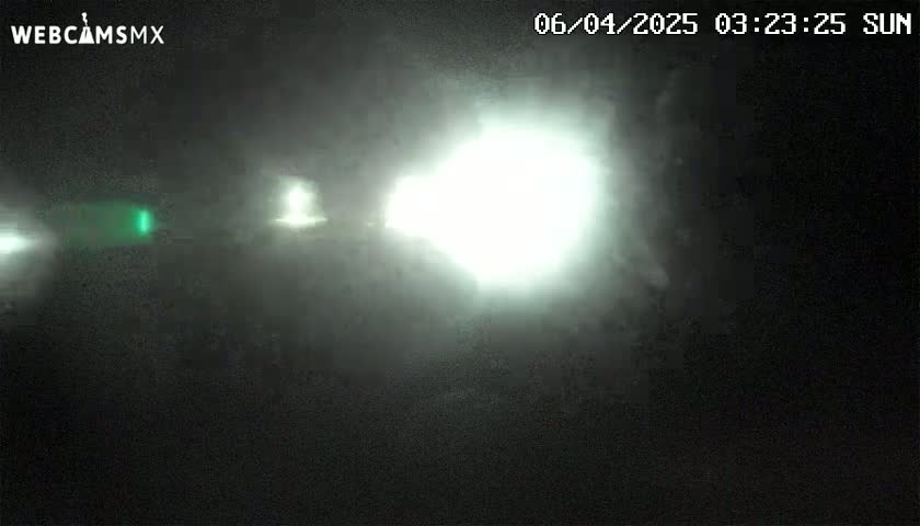 A bright light shines through a foggy, dark night.