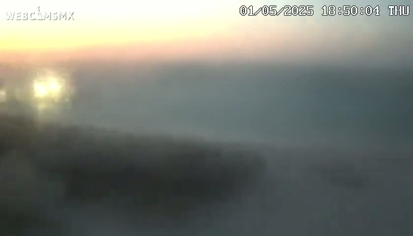 A hazy, sunlit landscape is visible through a blurry view, possibly due to fog or atmospheric conditions.