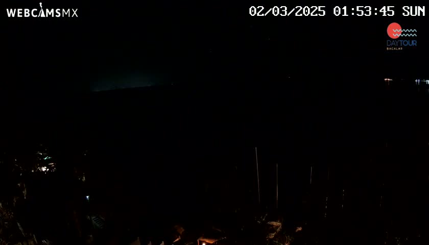 A nighttime, dark view of a body of water with a few distant lights visible in the distance.