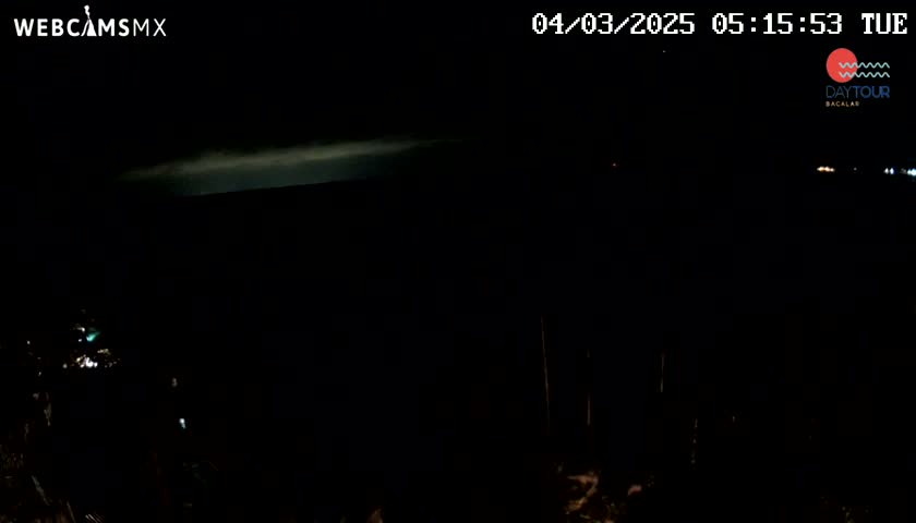 A nighttime, dark view shows a faint, light-colored band on the horizon under a mostly clear sky.