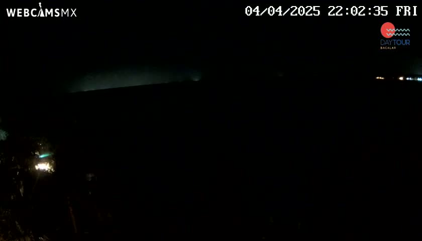 A nighttime, dark view shows a dimly lit horizon and faint lights in the distance.