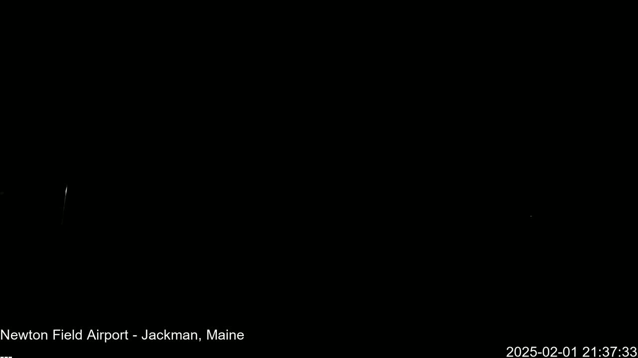 A nearly entirely black image shows a few faint lights in the distance at night.