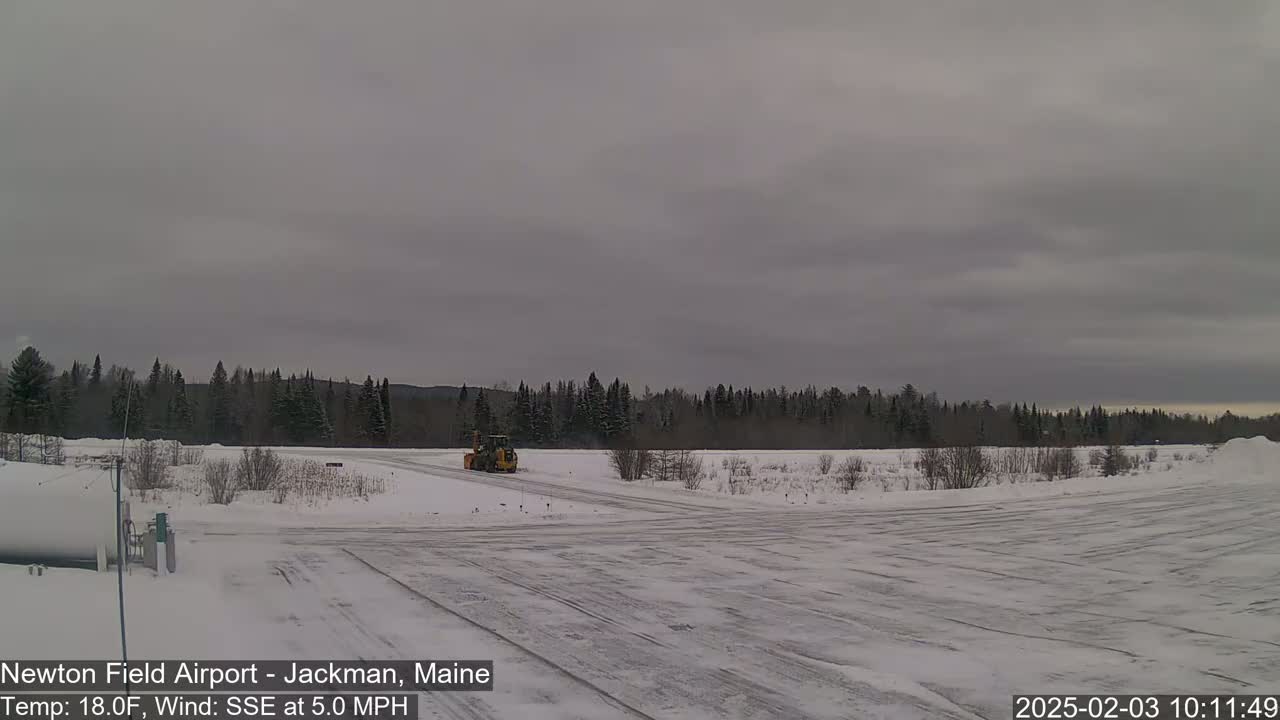A snow-covered airfield with a small yellow vehicle, under an overcast sky.